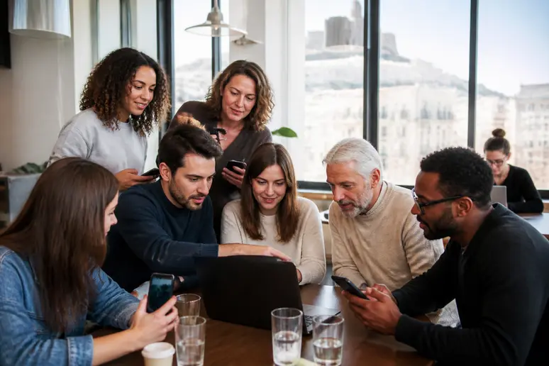 Des Français échangent autour de smartphones et d'un écran d'ordinateur, explorant le fonctionnement des cryptomonnaies dans un espace de coworking moderne.