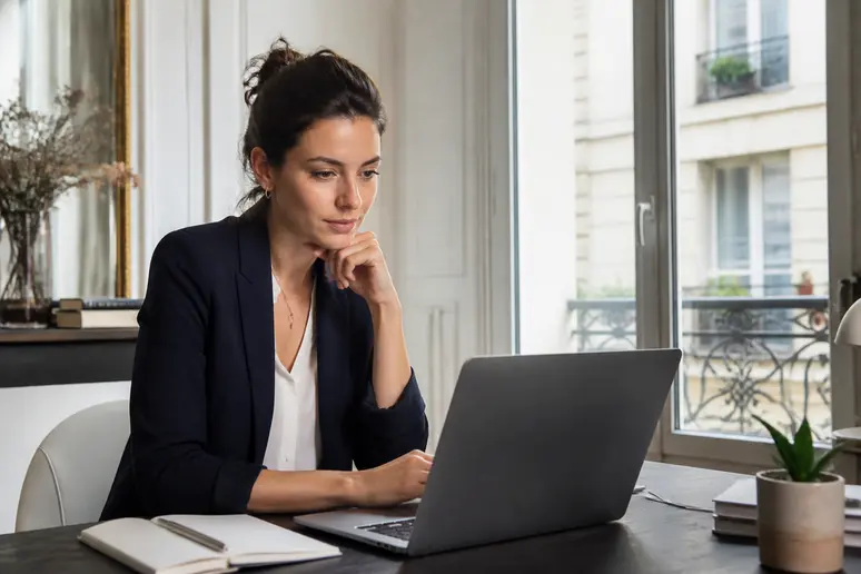 Une jeune femme à Paris analyse un tableau de bord de staking crypto sur son ordinateur portable, dans une lumière naturelle.