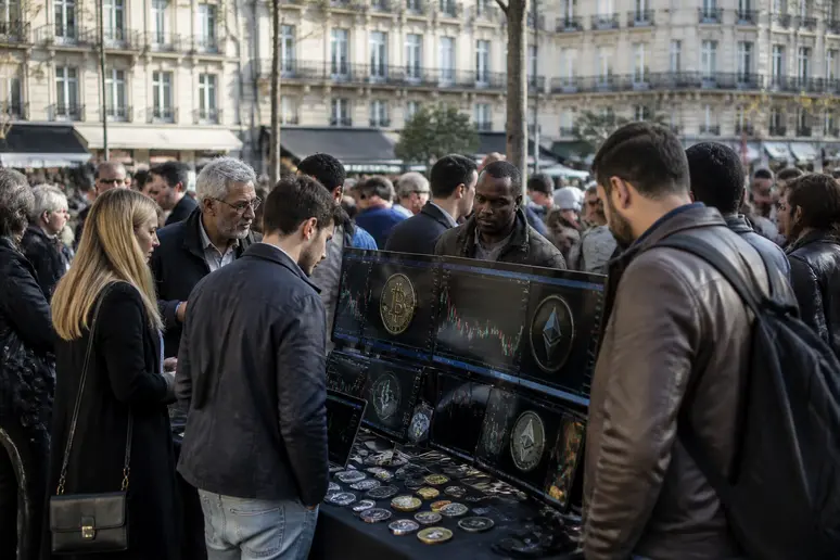 Un marché de cryptomonnaies en plein air animé, où des personnes observent des écrans affichant des graphiques financiers.