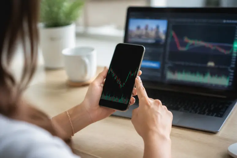 Mains d'une jeune femme utilisant un smartphone pour l'analyse technique bourse.