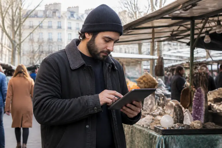 Un vendeur de marché à Paris utilise une tablette pour suivre les graphiques des cryptomonnaies avec une lumière naturelle du jour.