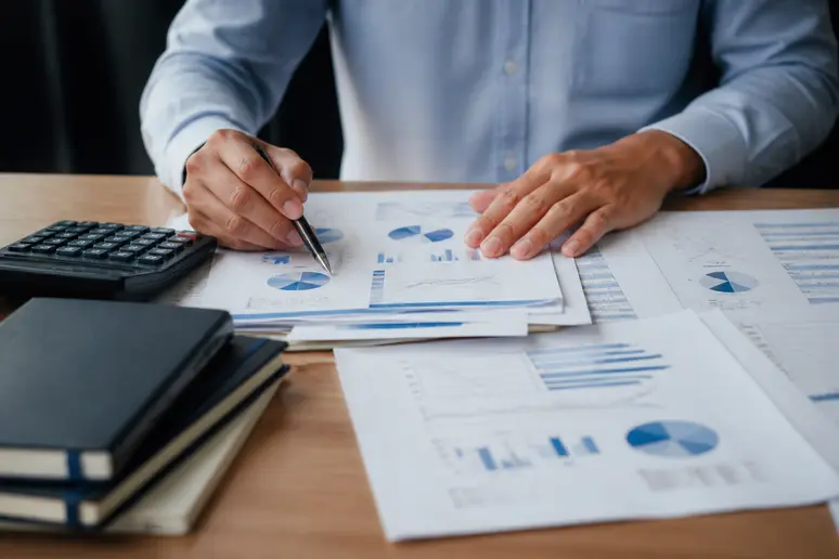Mains rangeant des documents financiers et vérifiant les arbitrages entre pea ou compte titre