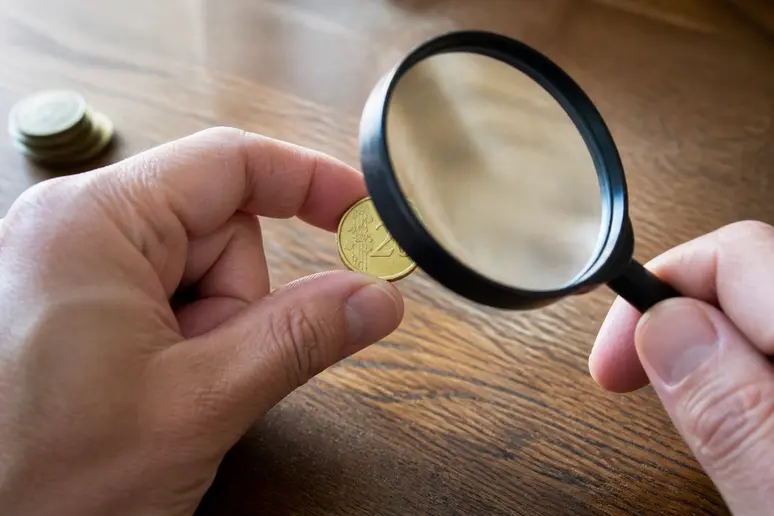 Un collectionneur examine attentivement les détails d'une pièce 20 centimes rare à la loupe