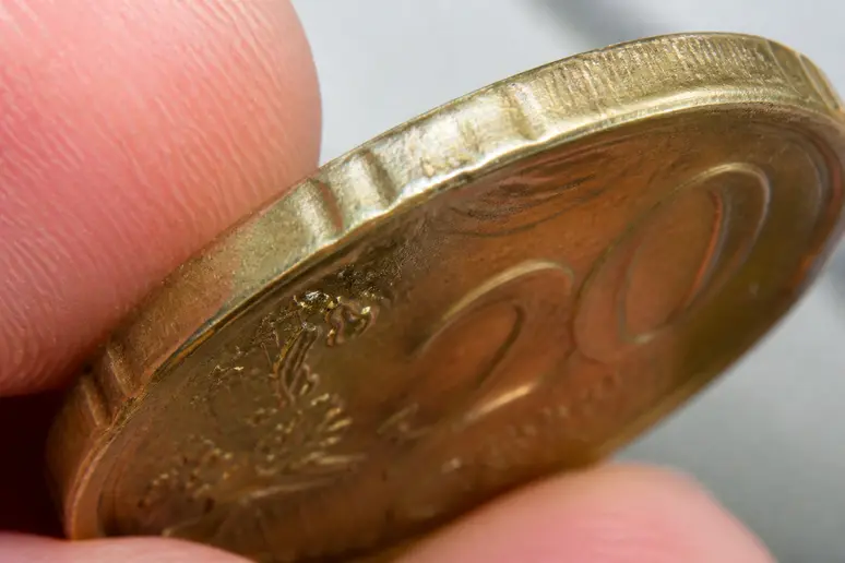 Inspection minutieuse de la tranche et des reliefs d'une pièce 20 centimes rare suspectée d'être fautée