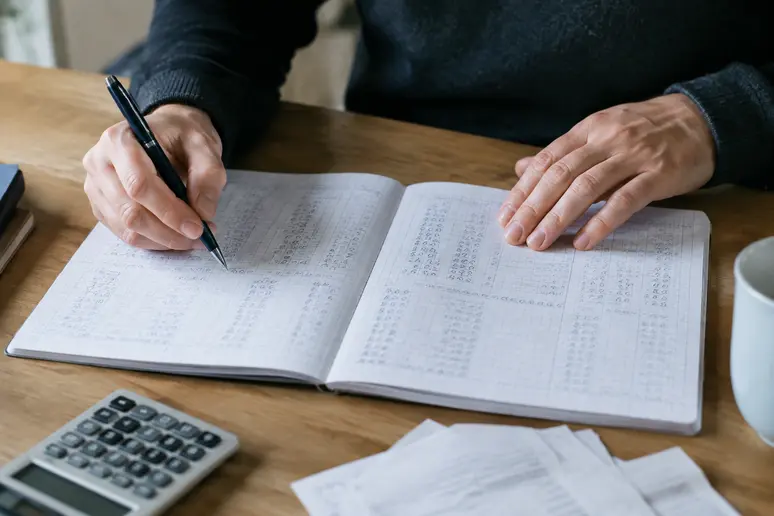 Mains consultant des calculs sur papier pour évaluer les plus-values réalisées sur un compte Binance.