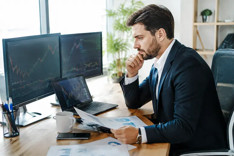 Investisseur analysant les graphiques boursiers et les indicateurs conjoncturels pour une action cyclique